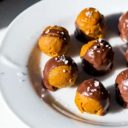 To make these tasty truffles, you will need the following ingredients: - 1 cup pumpkin puree - 1 cup cream cheese, softened - 1 teaspoon pure vanilla extract - 1 teaspoon ground cinnamon - &frac12; teaspoon ground nutmeg - &frac12; teaspoon ground ginger - &frac14; teaspoon ground cloves - 2 cups graham cracker crumbs - 1 cup caramel sauce, divided - 1 cup semi-sweet chocolate chips - A pinch of sea salt for garnish You can add a few fun things to make your truffles unique. Here are some ideas: - Finely chopped nuts for crunch - Different spices like allspice or cardamom - A splash of maple syrup for extra sweetness - Add a dash of cayenne for a spicy kick If you have dietary needs, you can swap some ingredients. Here are some options: - Use dairy-free cream cheese for a vegan version - Replace graham crackers with gluten-free crumbs - Swap semi-sweet chocolate chips for dark or milk chocolate - Use a sugar-free caramel sauce to lower sugar content This list gives you the basics and some fun options. Enjoy making these truffles your own! {{ingredient_image_2}} To start, grab a large mixing bowl. Add 1 cup of pumpkin puree and 1 cup of softened cream cheese. Then, pour in 1 teaspoon of pure vanilla extract. Next, sprinkle in your spices: 1 teaspoon of ground cinnamon, &frac12; teaspoon of nutmeg, &frac12; teaspoon of ginger, and &frac14; teaspoon of cloves. Use a hand mixer or whisk to blend these ingredients together. Keep mixing until the mixture is smooth. Take a moment to ensure there are no lumps. Then, take 2 cups of graham cracker crumbs and gradually add them to your pumpkin mix. Gently fold everything together. Your goal is to form a thick dough that holds its shape, but isn&rsquo;t too sticky. Now it&rsquo;s time to shape your truffles. Cover the bowl with plastic wrap and pop it into the fridge for about 30 minutes. This helps the mixture firm up. After chilling, scoop out portions with a tablespoon. Roll them into small balls, about 1 inch in diameter, and place them on a parchment-lined tray. Using your finger or the back of a spoon, create a small indentation in each truffle. Carefully fill these indentations with about a teaspoon of caramel sauce. Then, pinch the sides of the dough back together to fully cover the caramel. Once you&rsquo;ve filled them all, freeze the truffles for at least 15 minutes to help them set. While the truffles are freezing, it&rsquo;s time to melt the chocolate. Use a microwave-safe bowl and add 1 cup of semi-sweet chocolate chips. Melt the chocolate in 30-second intervals. Stir after each interval until the chocolate is completely smooth. Once melted, take the truffles out of the freezer. Dip each truffle into the warm chocolate, ensuring they&rsquo;re fully coated. Allow any extra chocolate to drip off before placing them back on the parchment-lined tray. Before the chocolate sets, sprinkle a tiny pinch of sea salt on top of each truffle. This adds a nice flavor contrast. Let them sit at room temperature until the chocolate hardens, or speed it up by placing them in the fridge. Enjoy your truffles as a tasty fall treat! To make sure your truffles stay soft and creamy, follow these steps: - Use fresh pumpkin puree; canned is fine, but fresh gives better flavor. - Soften the cream cheese fully before mixing. This helps create a smooth blend. - Mix gently when adding graham cracker crumbs. Too much mixing can make them tough. - Chill the mixture as directed. This helps it firm up just right for rolling. If your mixture turns out too sticky, don&rsquo;t worry! Here&rsquo;s how to fix it: - Add more graham cracker crumbs a little at a time. This can help absorb excess moisture. - Chill the mixture longer. A colder mix is easier to handle. - If you still struggle, wet your hands slightly while rolling. This can help prevent sticking. A smooth chocolate coating makes your truffles shine. Here&rsquo;s how to get it just right: - Use semi-sweet chocolate chips for a balance of sweetness. - Melt chocolate slowly in short bursts in the microwave. Stir between each burst until smooth. - Dip each truffle quickly to avoid melting. Let excess chocolate drip back into the bowl. - Sprinkle sea salt right after dipping. This adds flavor and enhances the look of each truffle. Pro Tips Use Fresh Pumpkin Puree: For the best flavor, consider using fresh pumpkin puree instead of canned. Roast a small pumpkin, scoop out the insides, and blend it until smooth. Chill the Truffles: After rolling the truffles, always chill them before dipping in chocolate. This helps them hold their shape and makes dipping easier. Experiment with Toppings: Don't just stop at sea salt! Try adding crushed nuts, pumpkin spice dust, or a sprinkle of cocoa powder for added flavor and texture. Storage Tips: Store the truffles in an airtight container in the refrigerator for up to a week. They can also be frozen for longer storage; just thaw before serving. {{image_4}} You can easily switch up the flavors in these truffles. For a minty twist, add peppermint extract to the pumpkin mix. This gives a fresh taste perfect for the holidays. If you love chocolate, try adding cocoa powder into the pumpkin mixture. This will create a rich chocolate pumpkin truffle. You can also use white chocolate instead of semi-sweet chocolate for a sweeter treat. Toppings can change the look and taste of your truffles. Try crushed nuts like pecans or walnuts for a crunchy finish. For a festive touch, use sprinkles or edible glitter. You can also drizzle melted chocolate or caramel sauce over the top. This adds flair and makes each truffle even more tempting. Making these truffles vegan is easy. Use coconut cream instead of cream cheese. Replace the caramel sauce with a vegan version made from coconut sugar and coconut milk. For gluten-free truffles, use gluten-free graham cracker crumbs. Always check the labels to ensure your ingredients are gluten-free. With these swaps, you can enjoy delicious truffles while meeting dietary needs. To keep your truffles fresh, store them properly. First, let the chocolate set completely. Then, place your truffles in an airtight container. Layer them with parchment paper to prevent sticking. Store in the fridge for up to two weeks. If you want to keep them longer, freeze them. Wrap each truffle in plastic wrap, then place them in a freezer-safe bag. They should last up to three months in the freezer. For the best taste, enjoy your truffles fresh. If you need to store them, keep the container closed. This helps keep moisture out. Avoid placing them near strong-smelling foods. Chocolate can absorb odors easily. For a quick snack, leave them at room temperature for up to an hour before eating. This will soften them and enhance the flavor. Check your truffles before eating them. If you see white spots, this may be fat bloom, which is safe to eat. However, if they smell off or have an unusual texture, it&rsquo;s best to toss them. A change in taste is another sign they are not fresh. Always trust your senses. If something seems off, it&rsquo;s better to be safe. Caramel pumpkin spice truffles last about one week in the fridge. If you store them in an airtight container, they stay fresh longer. You can also freeze them for up to three months. Just remember to let them thaw in the fridge before eating. Yes! Making these truffles in advance is a great idea. You can prepare them up to two days ahead. Just keep them in the fridge, covered, until you&rsquo;re ready to serve. If you freeze them, let them sit out for about 10 minutes before serving. This helps them soften a bit. You can find pre-made caramel pumpkin spice truffles at many gourmet shops and bakeries. Some grocery stores may also carry them in the fall. If you want to skip the store, you can make them at home with this easy recipe! Caramel pumpkin spice truffles are easy and fun to make. We covered all the key steps, from ingredients to storage tips. You can customize your truffles to match your taste, too. Remember to follow the guides to achieve smooth, creamy results. Enjoy crafting these treats for your friends and family. Make them vegan or gluten-free for extra options. Follow these tips, and you&rsquo;ll create delicious bites that everyone loves. Try these recipes, and impress everyone with your skills. Happy truffle making!