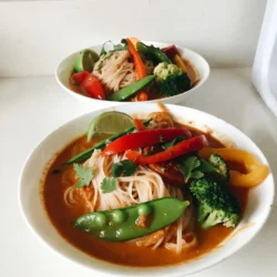 - 200g rice noodles - 1 can (400ml) of creamy coconut milk - 1 tablespoon fragrant red curry paste - 1 tablespoon vegetable oil - 1 medium onion, thinly sliced - 2 cloves of fresh garlic, minced - 1 tablespoon of freshly grated ginger - 1 bell pepper (any vibrant color), sliced into strips - 1 cup crisp snap peas, trimmed - 1 cup broccoli florets (fresh or frozen) - 2 tablespoons soy sauce (or tamari for gluten-free) - 1 tablespoon fresh lime juice - Fresh cilantro leaves, for garnish - Lime wedges, for serving Coconut curry noodle bowls pack a punch of flavor. You need rice noodles for that perfect base. The creamy coconut milk acts as a rich sauce. Red curry paste adds spice and depth. Finally, adding vegetable oil helps saut&eacute; the aromatics. Next, we bring in fresh vegetables. Onions add sweetness, and garlic gives a warm aroma. Ginger brightens the dish with its zing. Colorful bell peppers bring crunch. Snap peas and broccoli add vibrant texture. For seasoning, soy sauce provides umami. Fresh lime juice adds a bright kick. Garnish with cilantro for a fresh finish. Lime wedges on the side let you personalize each bite. Enjoy this tasty, satisfying meal! {{ingredient_image_2}} Start by boiling water in a large pot. Add the rice noodles and cook them according to the package instructions. This usually takes about 4-6 minutes. Once cooked, drain the noodles in a colander and set them aside. In a large pot or deep skillet, heat the vegetable oil over medium heat. Once hot, add the thinly sliced onion. Saut&eacute; for about 3-4 minutes, or until the onion becomes translucent and soft. Stir in the minced garlic and grated ginger. Cook for an additional minute, stirring frequently until the mixture becomes fragrant and aromatic. Add the red curry paste to the pot. Cook for about 2 minutes, stirring well. This helps the paste blend fully and develop its flavors. Pour in the creamy coconut milk, stirring gently to mix with the onion mixture. Allow this to come to a gentle simmer over low heat. Carefully add the sliced bell pepper, snap peas, and broccoli florets to the simmering coconut curry. Cook for 5-7 minutes, or until the vegetables are tender but still crisp. Stir in the soy sauce and freshly squeezed lime juice. Taste the mixture and adjust seasoning if needed. You can add more soy sauce for saltiness or lime juice for brightness. In serving bowls, evenly distribute the cooked rice noodles. Ladle the coconut curry mixture generously over the noodles. Be sure to mix in a good amount of vegetables and sauce in each bowl. Finish by garnishing each bowl with fresh cilantro leaves. Serve your coconut curry noodle bowls with lime wedges on the side. This lets everyone add an extra zing of flavor to their dish. To avoid mushy noodles, watch the cooking time. I recommend cooking rice noodles for just 4-6 minutes. Test them a minute early to ensure they stay firm. Drain them in a colander and rinse with cold water. This stops the cooking and helps keep them chewy. Adjusting spice levels can make this dish your own. If you want more heat, add a bit more red curry paste. For less spice, try using half the amount. You can also mix in chili flakes or fresh peppers. Always taste as you go! This way, you can find the perfect balance for your palate. To make this dish vegan, simply use vegetable oil and check your curry paste. Most red curry pastes are vegan, but always read the label. For gluten-free, swap soy sauce for tamari. The rest of the ingredients are naturally gluten-free. Enjoy this dish without worry! Pro Tips Perfect Noodle Texture: To achieve the ideal noodle texture, rinse the cooked rice noodles under cold water to stop the cooking process. This helps prevent them from becoming mushy. Customize Your Veggies: Feel free to swap in your favorite vegetables! Carrots, zucchini, or baby corn work wonderfully in this dish, allowing you to tailor the recipe to your taste. Enhance the Flavor: For an extra burst of flavor, consider adding a teaspoon of sugar or a splash of fish sauce to the curry base. This can help balance the richness of the coconut milk. Make It Ahead: This coconut curry noodle bowl can be made ahead and stored in the refrigerator for up to 3 days. Reheat gently on the stove, adding a splash of water or coconut milk to loosen it up. {{image_4}} You can add protein to your coconut curry noodle bowls for extra flavor. Here are some great options: - Tofu: Cube firm tofu and saut&eacute; it until golden. This adds a nice texture and absorbs the curry flavors well. - Chicken: Use diced chicken breast or thighs. Cook it in the pot before adding the garlic and ginger for a richer taste. - Shrimp: Add peeled shrimp during the last few minutes of cooking. They cook quickly and bring a lovely seafood flavor. Adjusting the spice level can make your dish fit your taste. Here&rsquo;s how: - Milder: Use less red curry paste or add more coconut milk. This will tone down the heat while keeping the flavor. - Spicier: Add extra red curry paste or a pinch of cayenne pepper. You can also serve it with sliced fresh chili on top for a spicy kick. Seasonal vegetables can change the dish's flavor and nutrition. Try these swaps: - Zucchini: Slice and add it for a fresh crunch. - Carrots: Use thinly sliced carrots for sweetness and color. - Spinach: Toss in fresh spinach at the end for a vibrant look and added nutrients. Feel free to get creative with these variations to make the dish your own! How do you store leftovers? Store your coconut curry noodle bowls in an airtight container. Make sure to cool the dish first. Place it in the fridge within two hours of cooking. This keeps the flavors fresh and safe to eat. The noodles can absorb moisture, so it's best to keep them separate from the curry if possible. Leftovers are good for up to three days. What are the best practices for freezing? If you want to freeze the dish, use freezer-safe containers. Let the curry cool down completely before you freeze it. Store the curry and noodles separately to prevent mushiness. You can freeze the curry for up to three months. When ready to eat, thaw it in the fridge overnight. What methods can you use for reheating without losing flavor? To reheat, you can use a microwave or stovetop. If using the microwave, heat in short intervals and stir often. For the stovetop, place the curry in a pot over low heat. Stir it gently until it warms up. If the curry is too thick after thawing, add a splash of coconut milk or water to bring it back to life. Enjoy your tasty meal! Yes, you can use many types of noodles. Here are some options: - Udon noodles: Thick and chewy, they soak up the curry well. - Soba noodles: Made from buckwheat, they add a unique flavor. - Egg noodles: These give a rich taste and texture. - Zucchini noodles: For a low-carb option, try spiralized zucchini. Feel free to experiment with your favorite noodles! Yes, this dish can be gluten-free. To make it so: - Use rice noodles instead of wheat noodles. - Replace soy sauce with tamari. Tamari is often gluten-free. Always check labels to ensure your ingredients are free from gluten. To add heat to your dish, try these tips: - Add more red curry paste for extra spice. - Include sliced fresh chili peppers in the curry. - Mix in chili flakes or sriracha for a kick. Adjust the spice to match your taste! These side dishes pair well with your Coconut Curry Noodle Bowls: - Spring rolls: Fresh or fried, they add crunch. - Asian slaw: A tangy slaw balances the curry. - Steamed rice: Serve it on the side for extra filling. - Pickled vegetables: They add a nice tang and contrast. Each choice brings something tasty to your meal! Coconut curry noodle bowls are simple and fun to make. We covered key ingredients like rice noodles, coconut milk, and fresh veggies. The step-by-step instructions show how to create a flavorful and satisfying dish. I shared tips that help you avoid mushy noodles and adjust spice levels. You can also swap proteins and vegetables for variety. This dish is versatile and easy to store. Enjoy this warm, comforting meal any day of the week. Cook with confidence, and let your taste buds rejoice!
